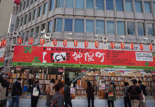 Outdoor bookstalls and browsers under the Kanda Used Book Festival banner in Jimbocho, Tokyo