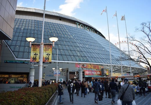 Tokyo Dome exterior with its signage, flags and crowds walking along the plaza in Bunkyo, Tokyo