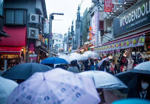 Umbrellas filling a Harajuku shopping street on a rainy afternoon in Tokyo