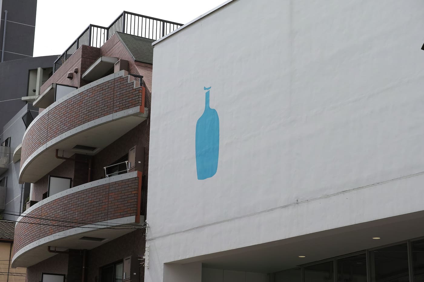White converted warehouse of Blue Bottle Coffee Kiyosumi with its blue bottle logo
