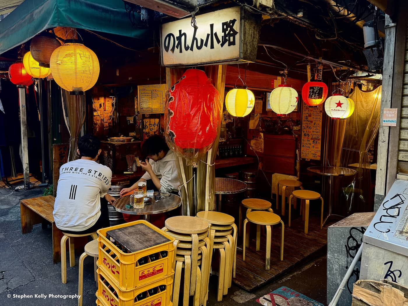 Drinkers at a lantern-hung open bar counter in Harmonica Yokocho, Kichijoji