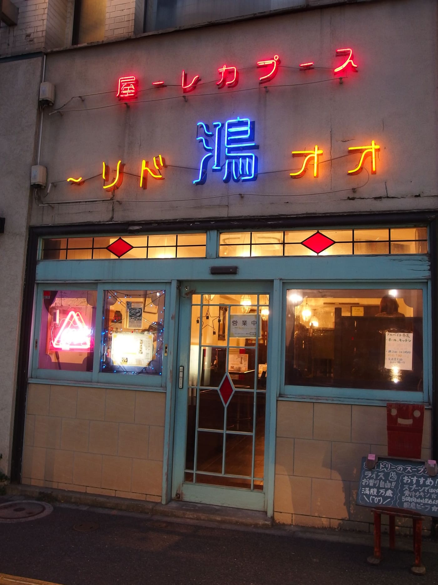 Neon-lit front of a long-running curry house on a Jimbocho street at dusk