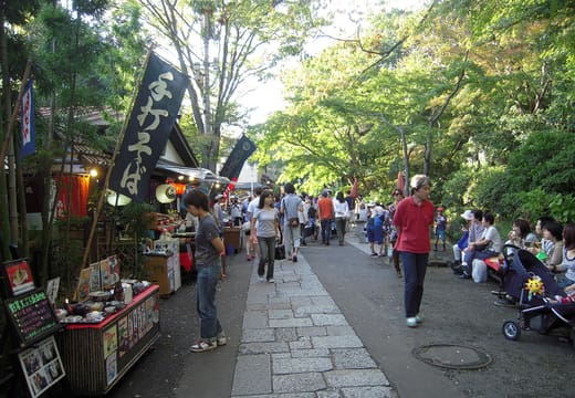 Visitors walking the stone Jindaiji temple approach past soba shops and snack stalls