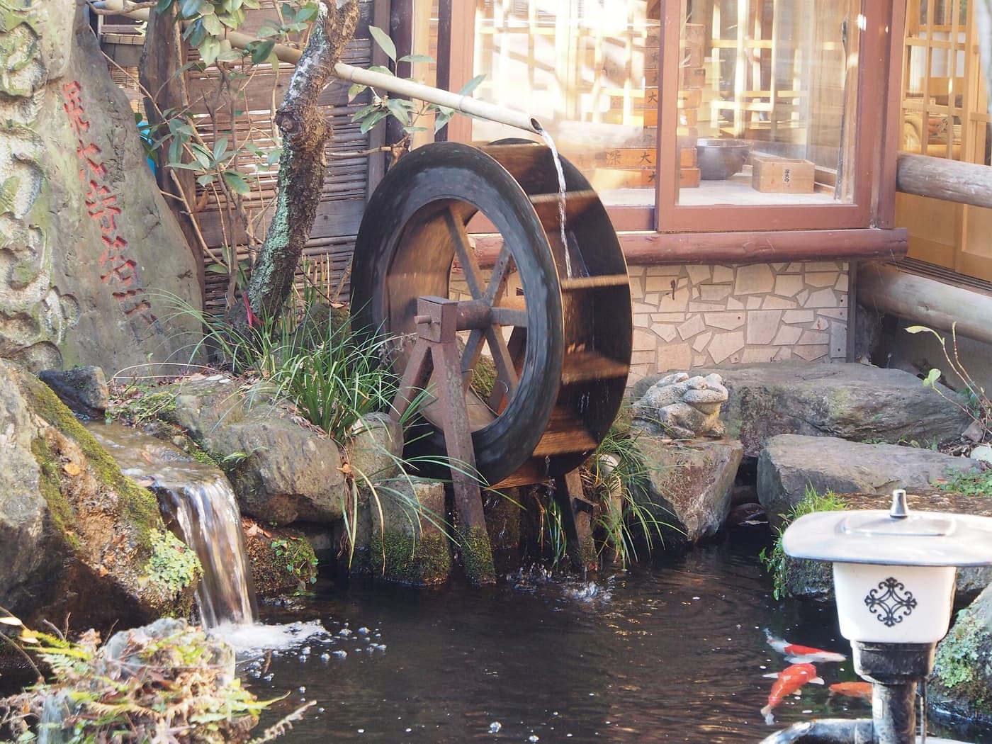 Wooden water wheel turned by spring water beside a shop on the Jindaiji approach