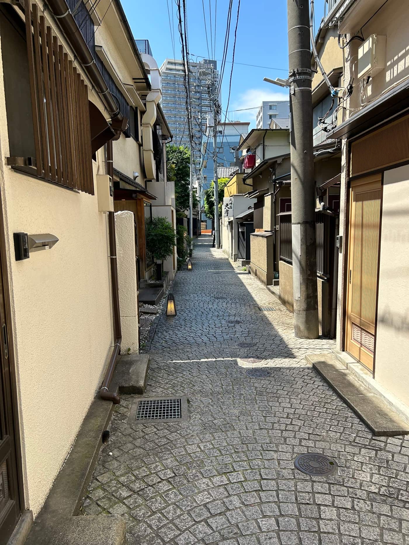 Cobbled Kagurazaka backstreet lined with low traditional houses on a bright day
