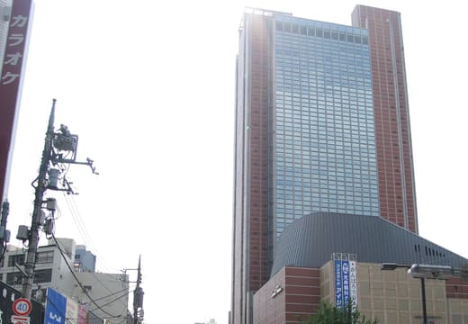 Cyclists crossing Setagaya-dori in Sangenjaya beneath Carrot Tower and the station buildings