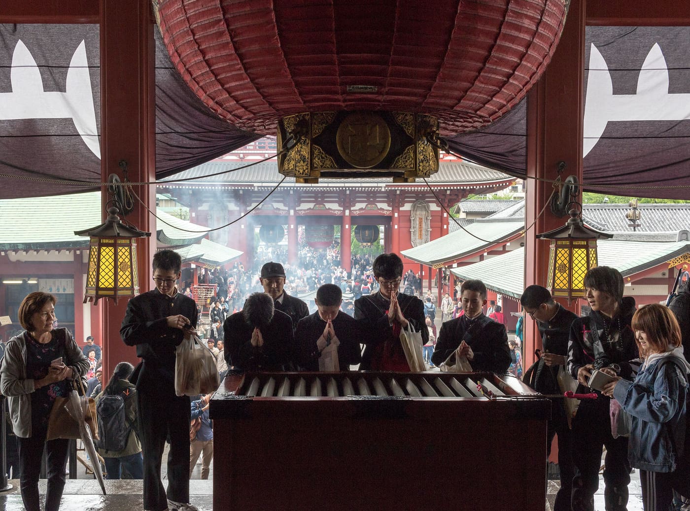 Visitors wafting incense smoke at the burner in front of the Senso-ji main hall