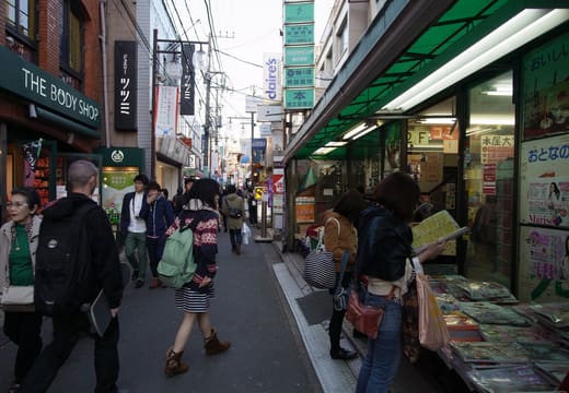 Shoppers walking a narrow Shimokitazawa shopping lane lined with small stores and awnings