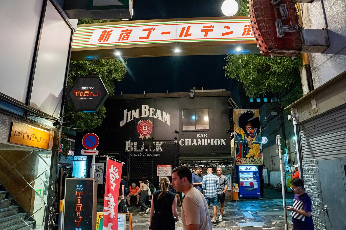 Lit entrance arch of Shinjuku Golden Gai with its tiny bar alleys at night