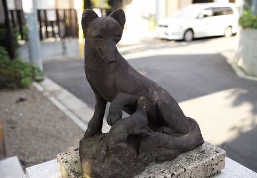 Weathered stone fox guardian at the Inari shrine within Akagi Shrine grounds, Kagurazaka