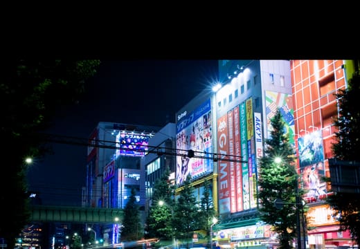Traffic light trails past the neon towers of Akihabara Electric Town at night