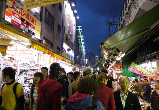 Evening crowds between brightly lit food stalls on Ameyoko market street, Ueno