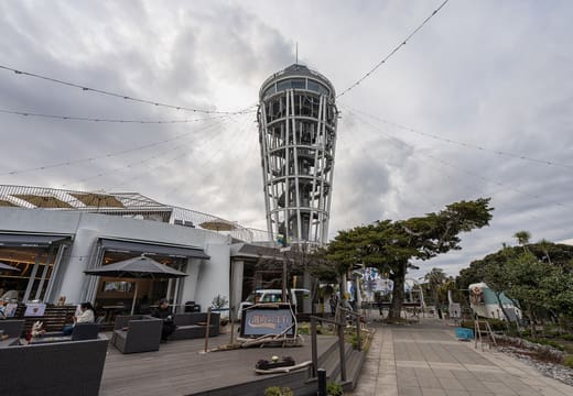 Enoshima Sea Candle observation lighthouse rising over the island's hilltop garden in daylight
