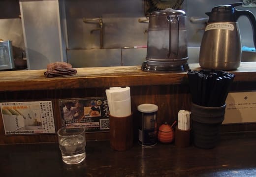 Counter seating with water jugs and condiments inside Fuunji ramen shop, Shinjuku