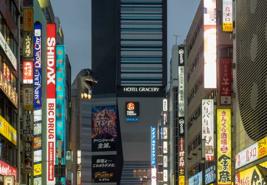 Godzilla head on the Hotel Gracery building at dusk above neon signs of Kabukicho, Shinjuku