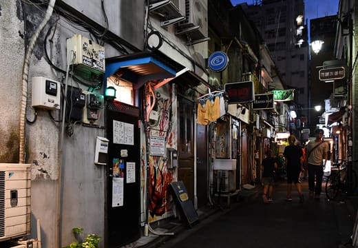 Narrow Golden Gai alley lined with tiny bars and their hanging signs in Shinjuku