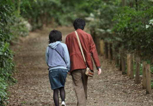 Couple walking a gravel path through the dense forest of the Institute for Nature Study