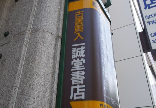 Green and gold vertical signboard of Isseido Booksellers on its stone corner in Jimbocho