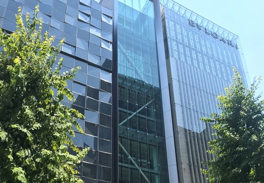 Slim glass tower of the Itoya Ginza stationery store between trees on Chuo-dori