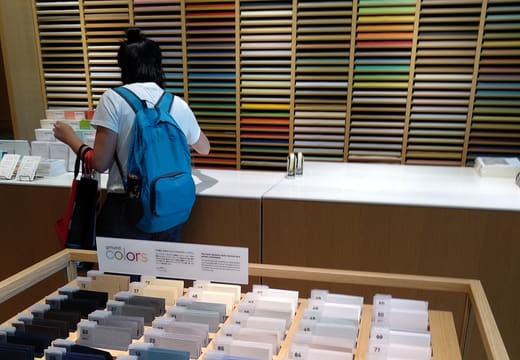 Shopper choosing from a wall of coloured Gmund papers at Itoya Ginza