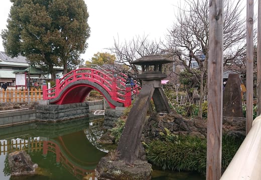 Shinji pond with stone lantern and red arched bridge at Kameido Tenjin Shrine