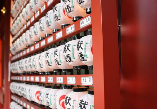 Rows of white paper lanterns lining a vermilion wall at Kanda Myojin Shrine
