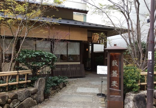 Stone garden path and wooden signboard at the entrance of Kanda Yabu Soba