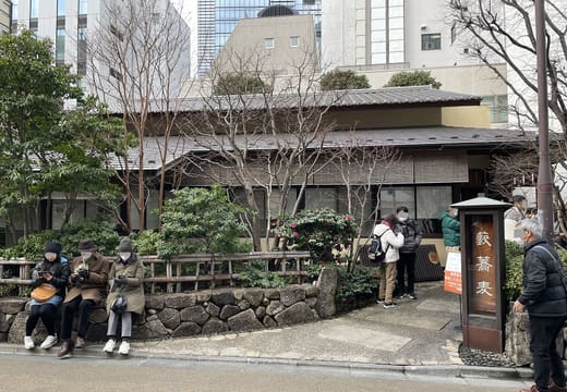 Diners waiting outside the rebuilt Kanda Yabu Soba behind its garden wall in Kanda