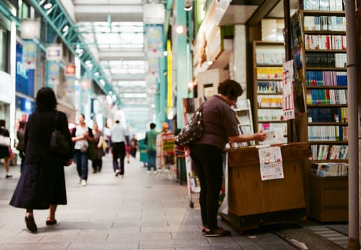 Shoppers and a bookstall along a covered shopping arcade near Kichijoji Station