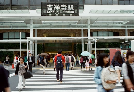 Crowds crossing in front of JR Kichijoji Station under its station name sign