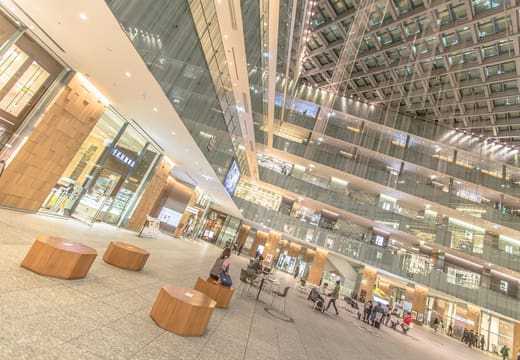 Triangular glass atrium with wooden benches inside KITTE Marunouchi