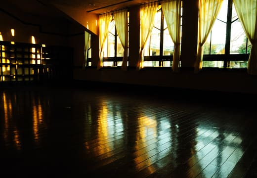 Evening light on the polished floor and yellow curtains of the Myonichikan dining hall
