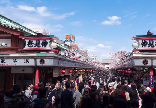 Crowds walking Nakamise shopping street between souvenir stalls toward the Hozomon gate, Asakusa