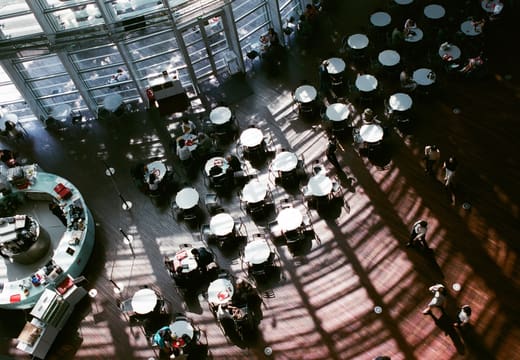 Cafe tables seen from above in the soaring glass atrium of the National Art Center Tokyo