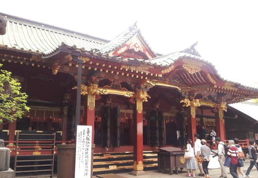 Lacquered red and gold worship hall of Nezu Shrine with visitors in the courtyard