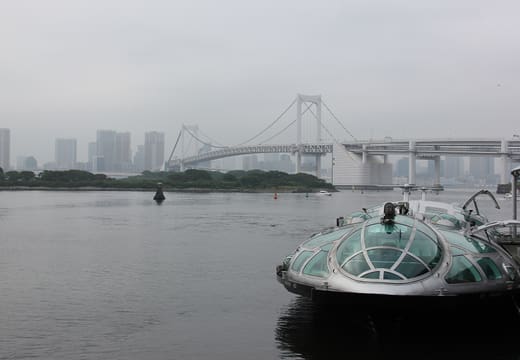 Futuristic Himiko water bus arriving at Odaiba Seaside Park below Rainbow Bridge