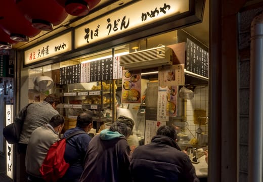 Diners crowding a tiny counter stall for dinner in Omoide Yokocho, Shinjuku