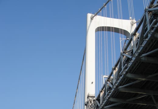 White suspension tower and cables of Rainbow Bridge against a blue sky