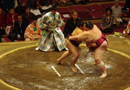 Two wrestlers locked in a bout on the dohyo during a tournament at Ryogoku Kokugikan