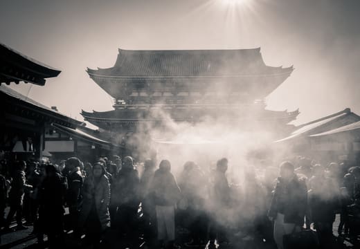 Worshippers wafting incense smoke from the burner in front of the Senso-ji main hall