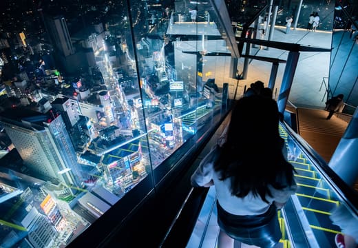 Visitor riding the Shibuya Sky escalator above the glowing city lights at night