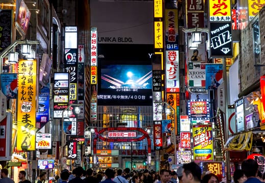 Dense neon signs and screens over a crowded Shinjuku street at night