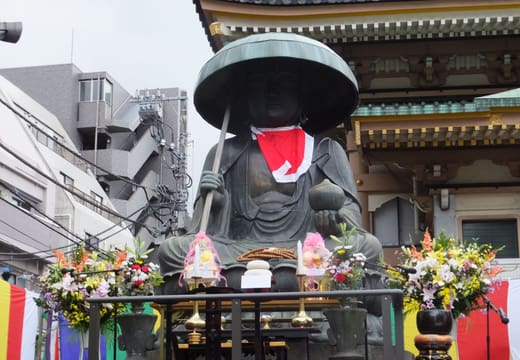 Large bronze Jizo statue with a red bib at Shinshoji at the start of Sugamo Jizo-dori