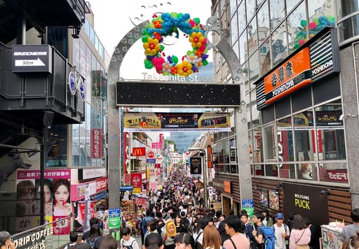 Crowds pouring under the colourful Takeshita Street entrance gate in Harajuku