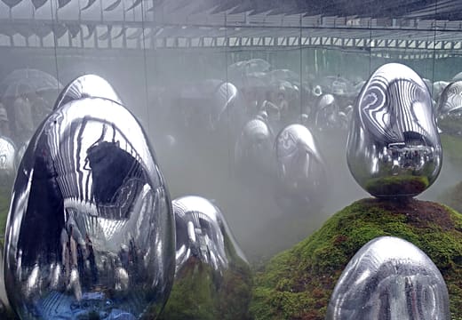 Mirrored egg sculptures glowing in mist on a moss floor at teamLab Planets, Toyosu