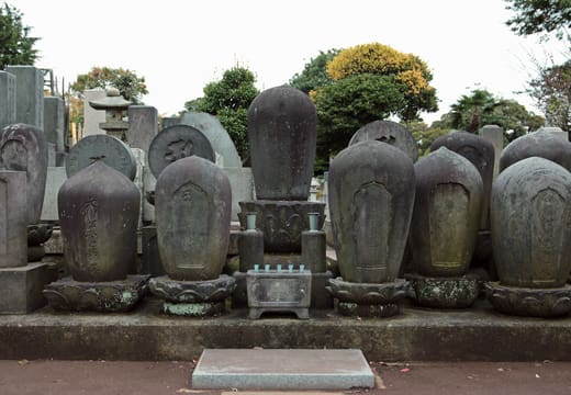 Row of weathered rounded gravestones among the family plots of Yanaka Cemetery