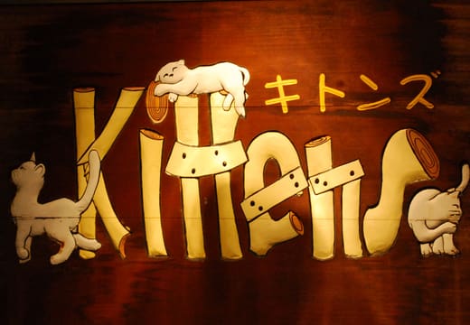 Wooden shop sign decorated with carved cats on Yanaka Ginza, the street known for its cats
