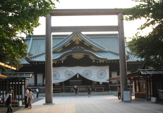 Worship hall of Yasukuni Shrine framed by a wooden torii with white chrysanthemum curtains