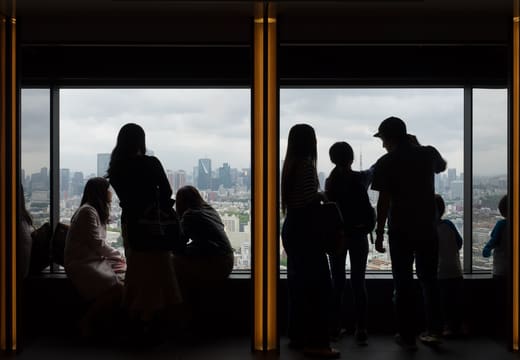 Visitors silhouetted at the windows of the free sky lounge in Yebisu Garden Place Tower