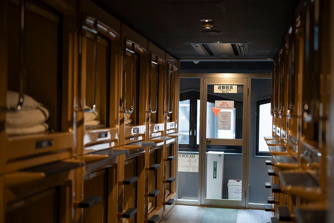 A corridor of wooden capsule pods in a Shinjuku capsule hotel